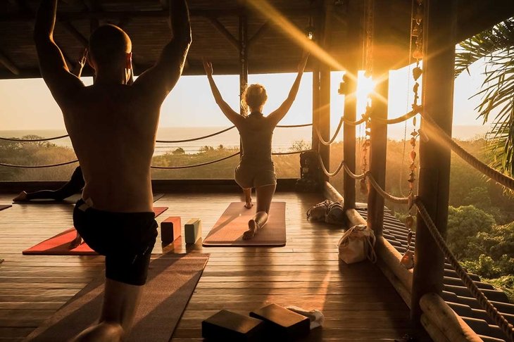 tropical open yoga studio place with people and a view outside to the ocean while sunset